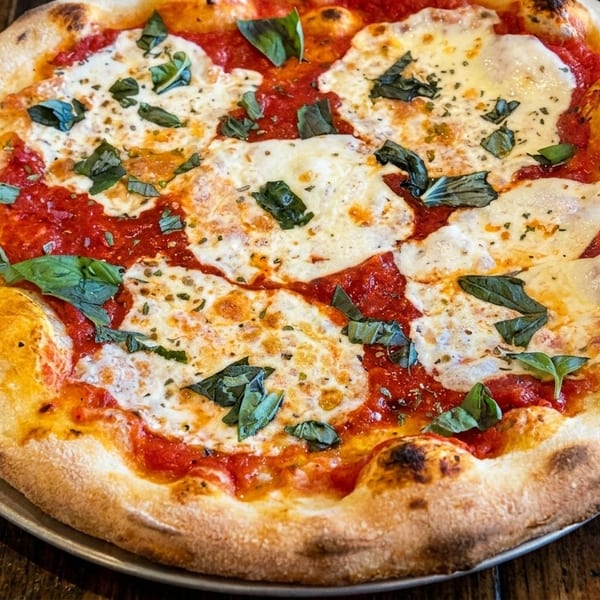 A freshly baked Margherita pizza with melted mozzarella, red sauce, and basil on a wooden table.