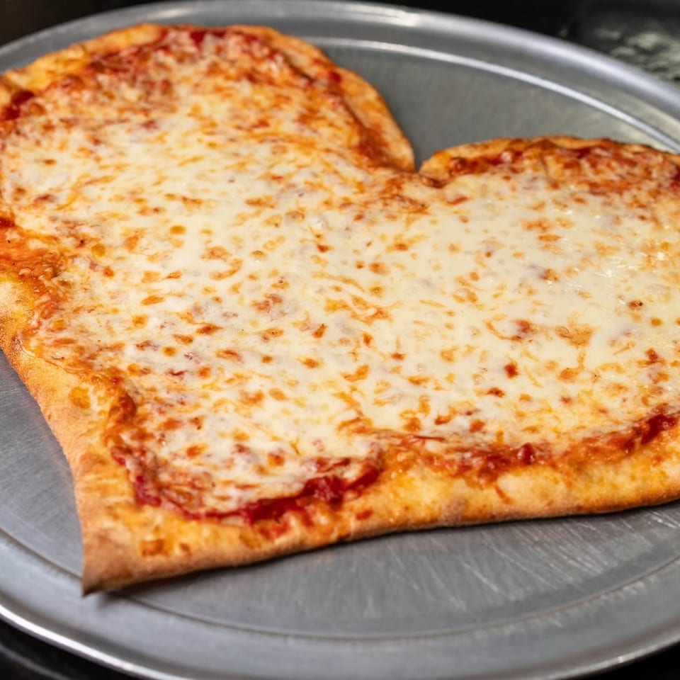 Large rectangular cheese pizza with a golden crust and tomato sauce on a round metal serving tray.
